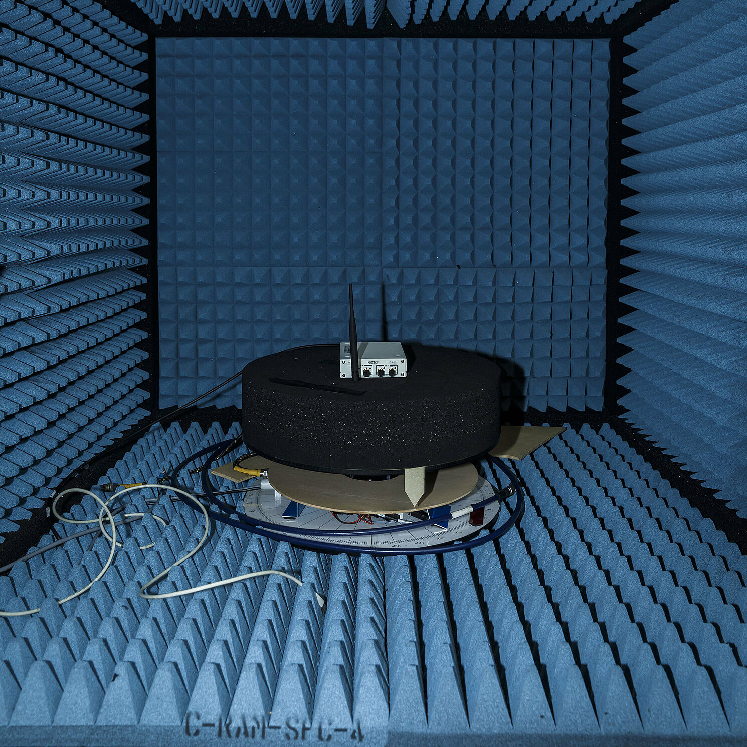 Hochfrequenz Sende-/Empfangseinheit in einer Antennenmesskkammer, die an fünf Seiten mit reflexionsdämpfendem Material ausgekleidet ist.